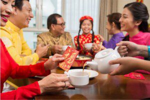 Someone pouring tea for another person at a table, a gesture of respect and gratitude in Chinese dining etiquette